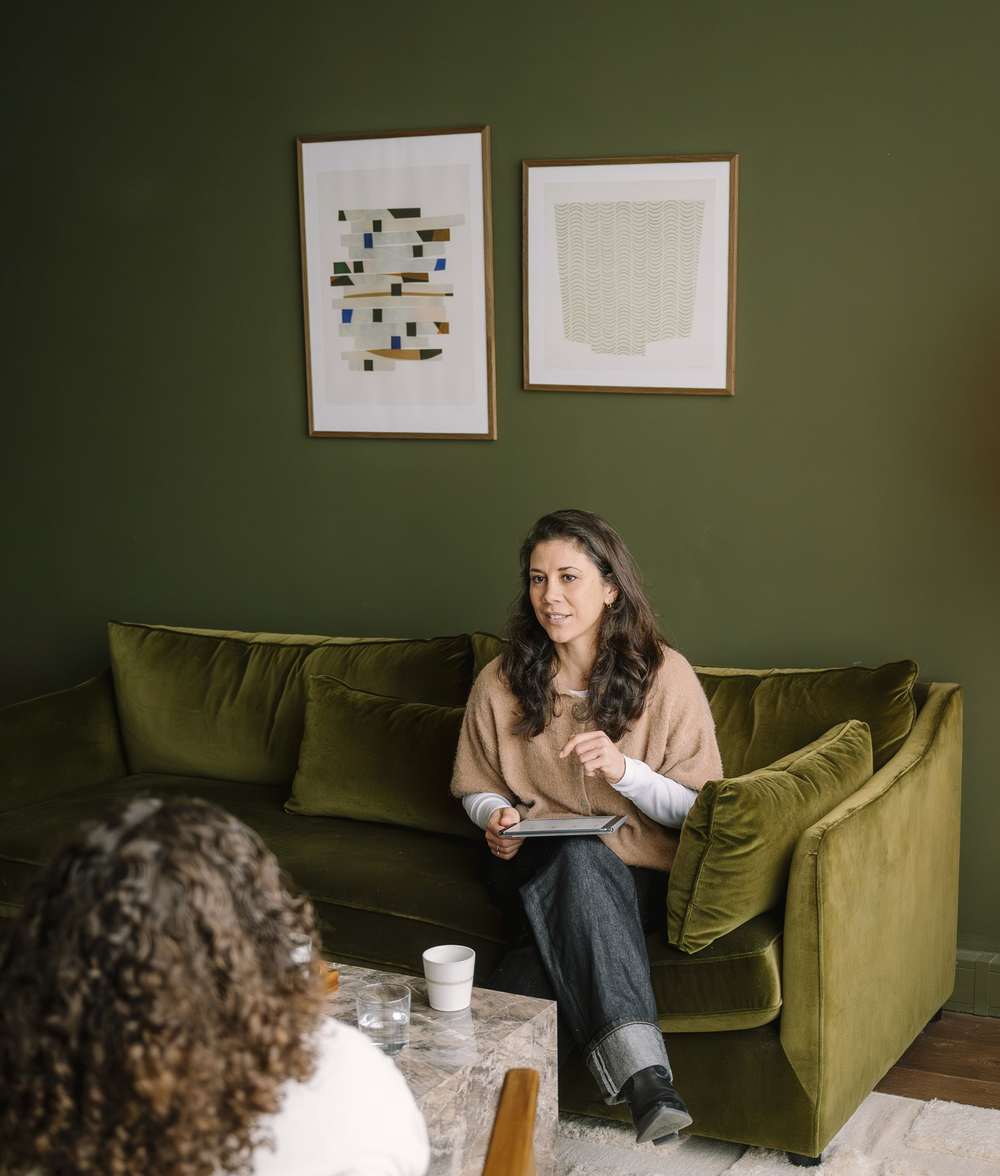 Iris op de groene bank in gesprek met een cliënt